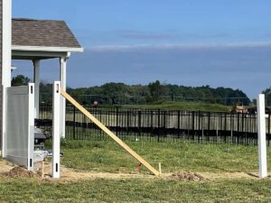 Fence posts being installed with a black metal fence in the background, showing work by Morton Fence Solutions LLC in Indianapolis, IN.