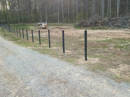 Fence posts and wire mesh being installed along a property line by Almaraz & Sons LLC in Macon, GA.