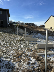 Fence posts installed on a snowy, sloped backyard for a new fence installation by Flash Fence in Phenix City, AL.