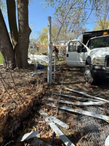 A fencing contractor working on fence removal and installation with a truck on site by Matul Fence Inc in Lynn, MA