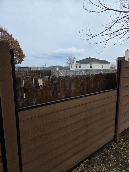 A fence showing a combination of old wooden pickets and new composite panels, indicating a repair or upgrade by NTX-Exterior Services in Dallas, TX.