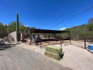 A fencing contractor from TACK Fabrication installing a metal animal pen enclosure in Romero, Tucson, AZ.
