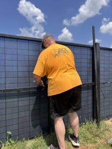 A fencing contractor installing a solar panel onto a fence structure for Sol Fence LLC in Evansville, IN.