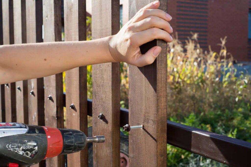 A fencing contractor installing a wood fence picket with a drill, showcasing the installation process by Longhorn Fencing Eastern Idaho in Pocatello, ID.