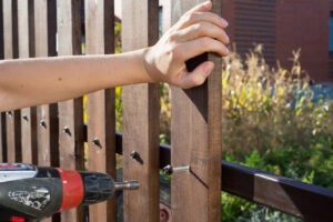 A fencing contractor installing a wood fence picket with a drill, showcasing the installation process by Longhorn Fencing Eastern Idaho in Pocatello, ID.