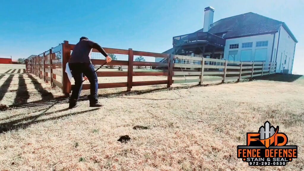 A fencing contractor installing a long wood rail fence in a large open field for Fence Defense, LLC in Plano, TX.