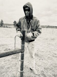 A fencing contractor working on a fence post in a field, representing Cool Hand Fencing and Wyo War Wagons in Laramie, WY.