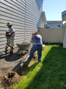 Fencing contractors from Double A Fence LLC digging post holes with an auger for a new fence installation in Boise, ID.