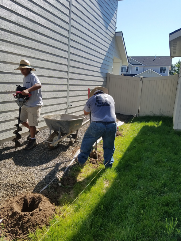 Fencing contractors from Double A Fence LLC digging post holes with an auger for a new fence installation in Boise, ID.