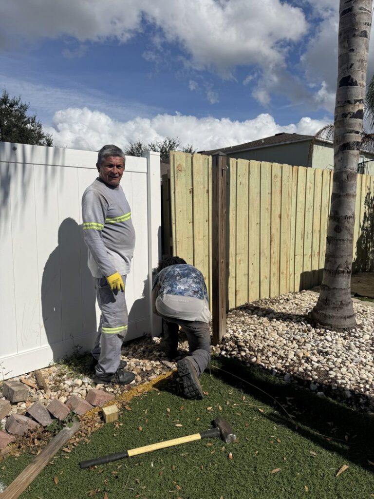 Fencing contractors from Santis Fence & Home Service installing a wood fence section in Tampa Heights, FL