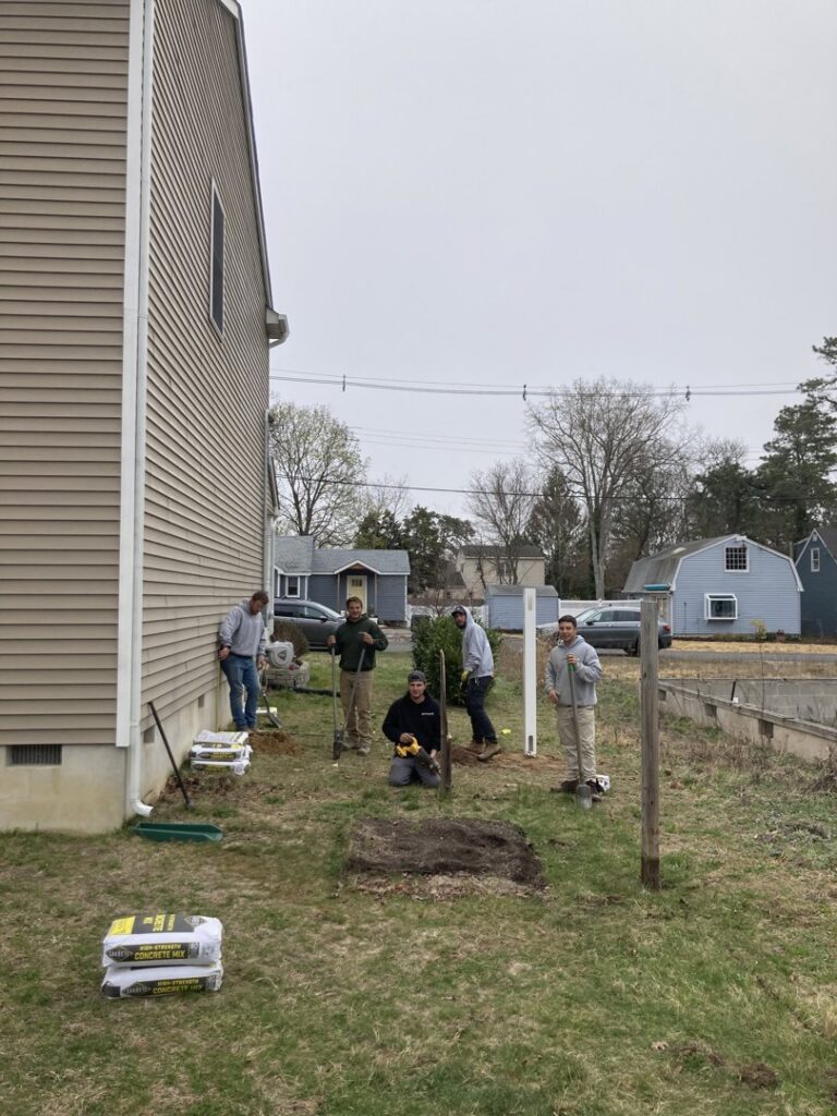 A fencing crew from MAC Fencing LLC installing fence posts in a residential yard in Toms River, NJ