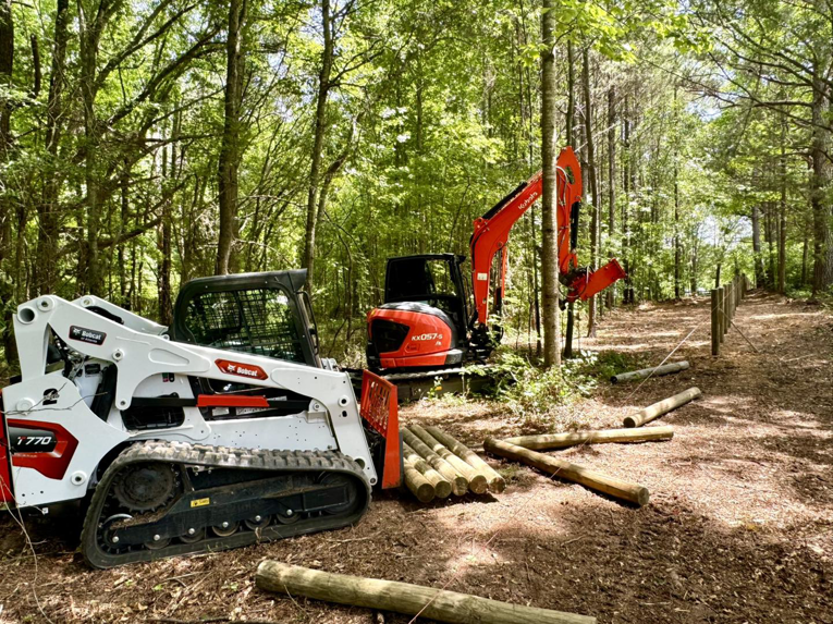 Heavy equipment and wooden fence posts ready for installation by Smith Land and Farm in Mansfield, GA