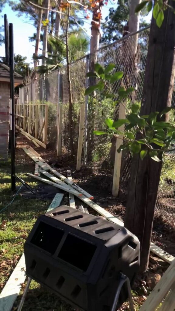 A fencing job in progress showing new wooden posts and existing chain link fence by GOAT Fence Company in Houston, TX.