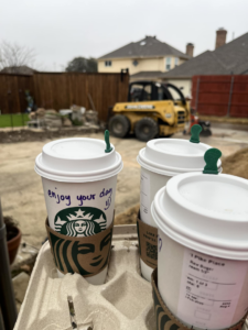 A fencing job site with Starbucks coffee cups and a skid steer, showing work in progress by Reliable Texas Fencing in Fort Worth, TX.