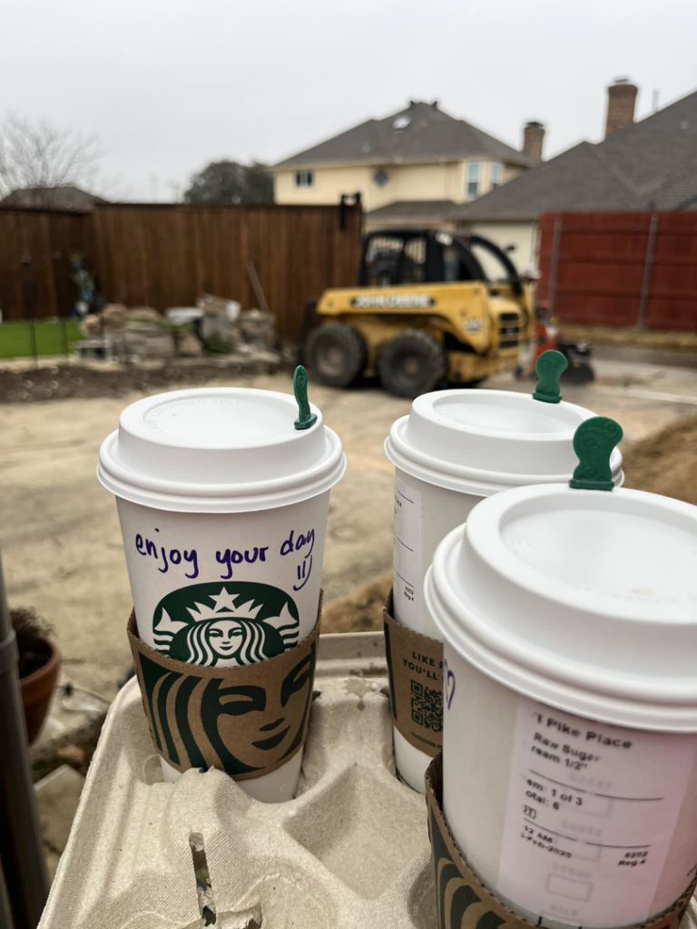A fencing job site with Starbucks coffee cups and a skid steer, showing work in progress by Reliable Texas Fencing in Fort Worth, TX.