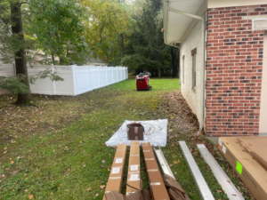 Fencing materials on the ground next to a newly installed white vinyl fence by Fence Guys INC in Cleveland, OH.