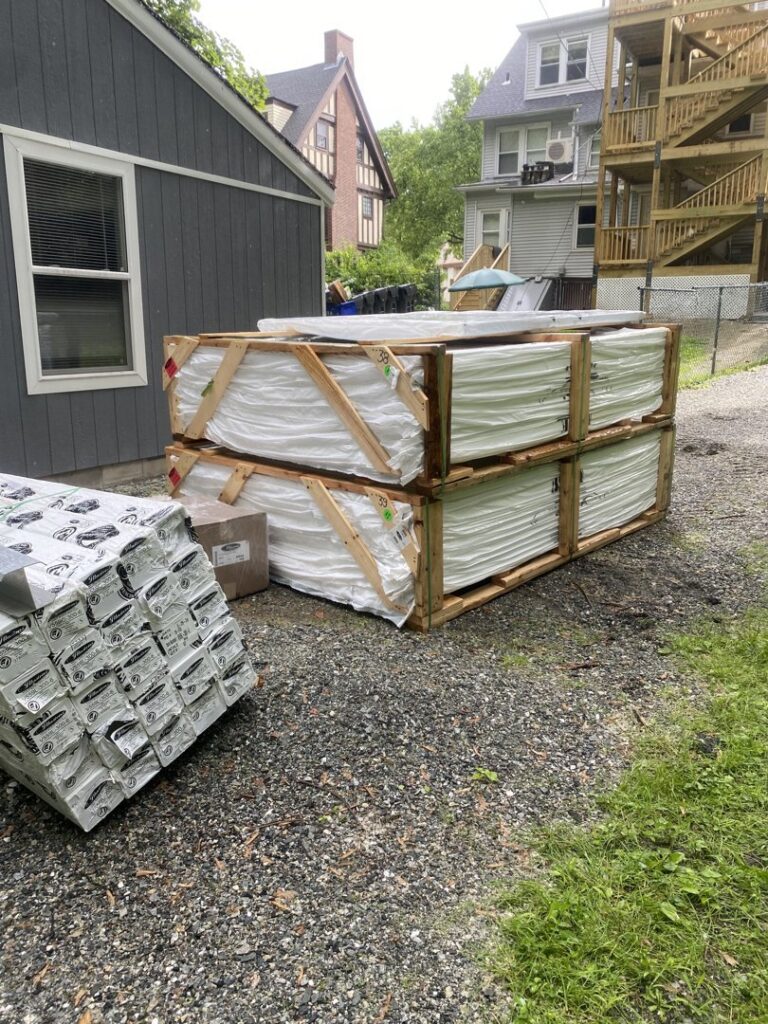 Crates of white vinyl fencing panels and materials ready for installation by Texeira Fencing & Concrete in Springfield, MA.