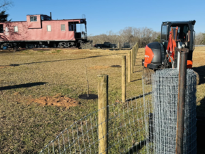 Fencing materials, wooden posts, and equipment in a field by Smith Land and Farm in Mansfield, GA