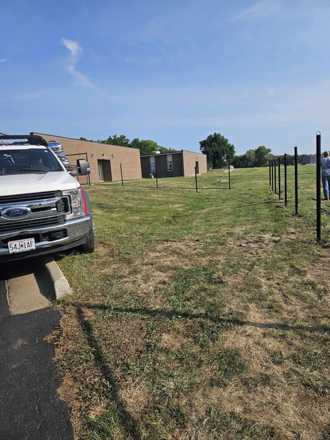 A work truck parked near fence posts being installed for a new fencing project by Atchison Fence in Effingham, KS.