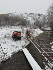 Fencing work in progress with an excavator near a stream, handled by Deer Creek Ag Services in Ranchester, WY.