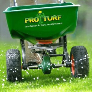 A Pro Turf branded fertilizer spreader applying granular product to a lawn, part of turf and pest solutions by Nebraska Pro Turf & Pro Pest Solutions in Omaha, NE.