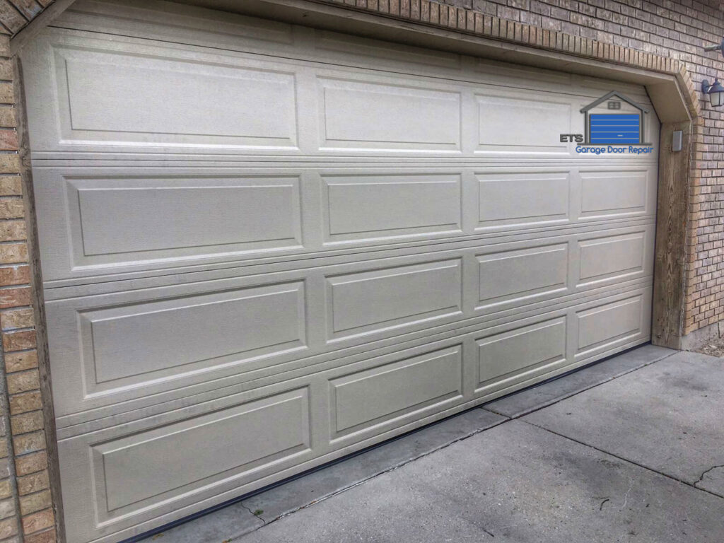 A finished beige garage door installation on a residential home by ETS - Garage Door & Electric Gate Repair Of Bellevue, WA.