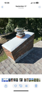 A newly repaired and installed chimney with a metal cap on a residential roof by Harry's Quality Chimney Services in Kansas City, MO
