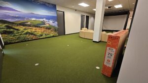 A finished room with green artificial turf carpet and a large screen by At Home Flooring in Naperville, IL.