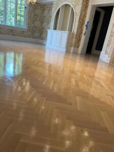 A beautifully finished herringbone pattern hardwood floor in a spacious room by Isad Home Floor in Bridgeport, CT.