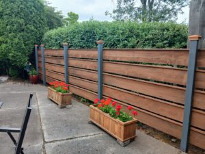 A finished horizontal slat fence with dark posts and wooden planter boxes, installed by Fence Repair Master in Vancouver, WA.