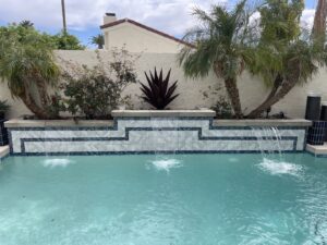 A beautifully finished swimming pool with a decorative waterfall feature, installed by All Valley Pools in Avondale, AZ.