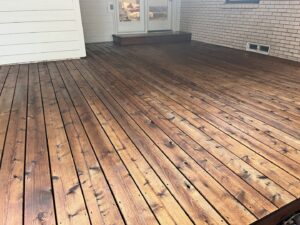 A beautifully finished stained wooden deck in a residential backyard, completed by Fence Defense, LLC in Plano, TX.