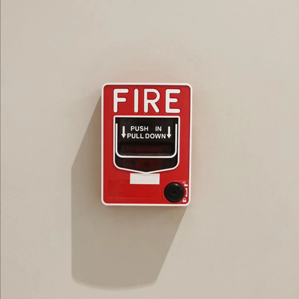 A red fire alarm pull station, representing electrical safety system installation by MC2 Electric Inc. in San Francisco, CA.