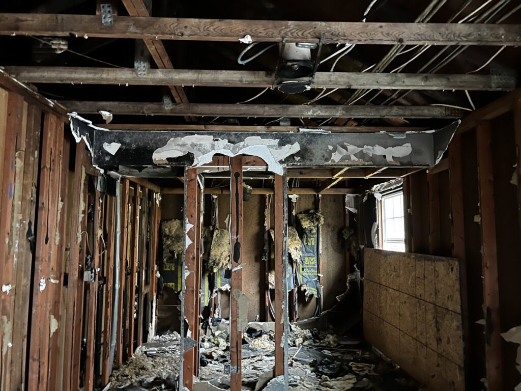Fire-damaged electrical wiring and structural elements in a room, indicating a need for repair by Buckeye Electric of Upper Arlington, LLC in Columbus, OH.