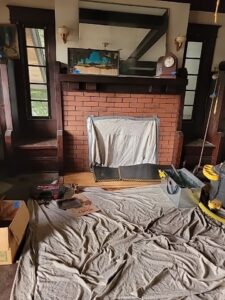 A fireplace area meticulously prepared with drop cloths and tools for a chimney sweep by Burning Bush Chimney Service in Wood Village, OR.