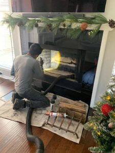 A professional from 832 Home Service performing a thorough fireplace cleaning as part of a chimney sweep in Houston, TX.