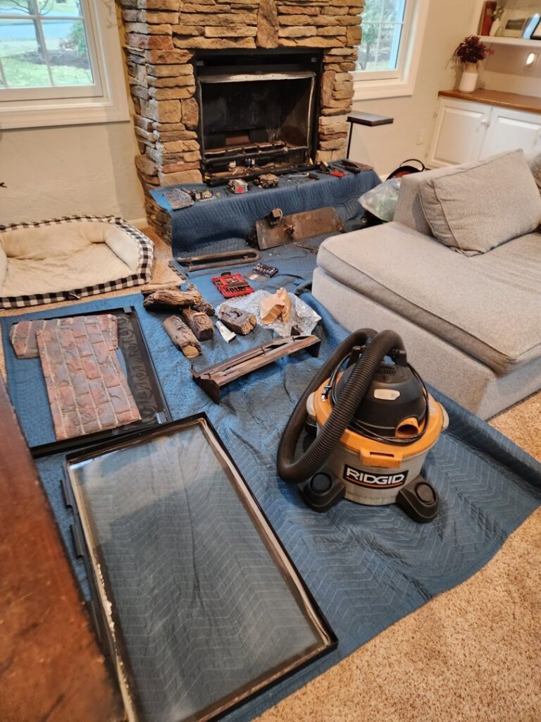 Fireplace area with drop cloths, tools, and disassembled parts during a cleaning or repair service by Top Dog Hearth Repair & Maintenance, LLC in Worcester, MA