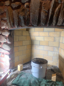 Fireplace firebox repair in progress with tools and a debris bucket by The Chimney Sweep in Stafford, VA.
