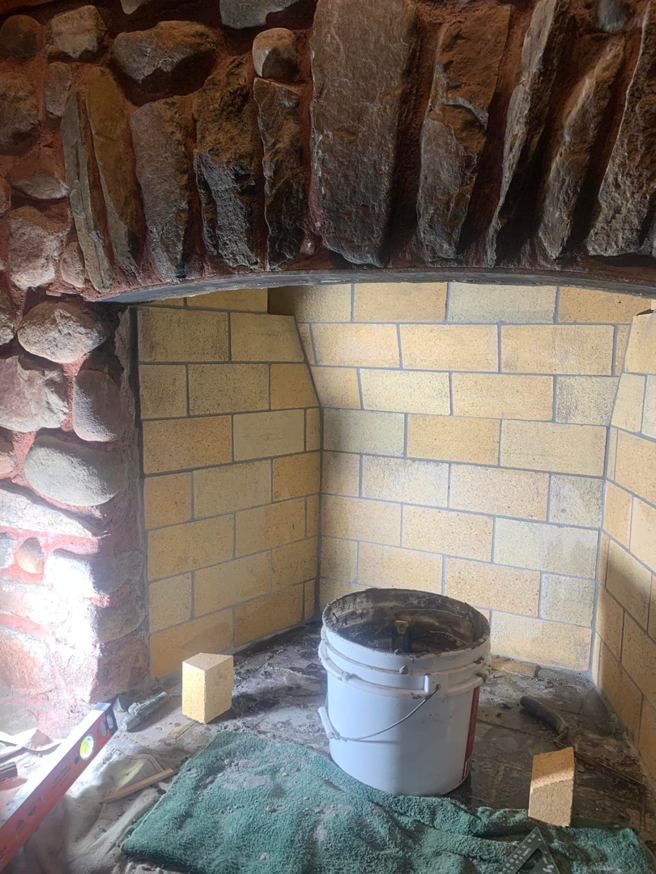 Fireplace firebox repair in progress with tools and a debris bucket by The Chimney Sweep in Stafford, VA.