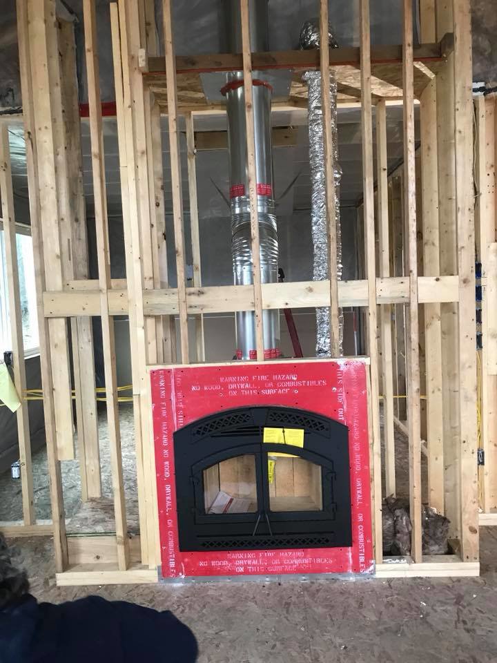 A new fireplace insert and flue system being installed in a framed wall by Boiler Man Plumbing & Heating in Palmer, AK