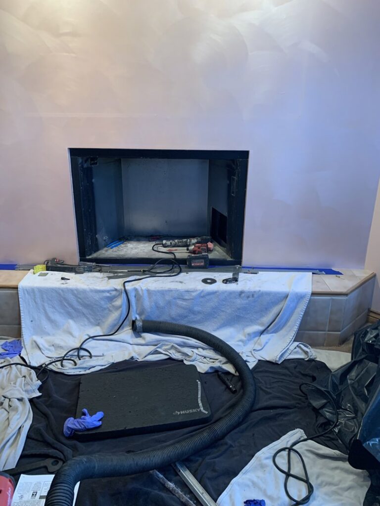 A fireplace opening prepared for cleaning with protective sheeting, tools, and a vacuum hose by Ignite Chimney & Fireplace in Chicago, IL.