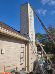 A fireplace interior with brass elements, protected by plastic on the floor for a chimney sweep service by Brushers Chimneys in Houston, TX.