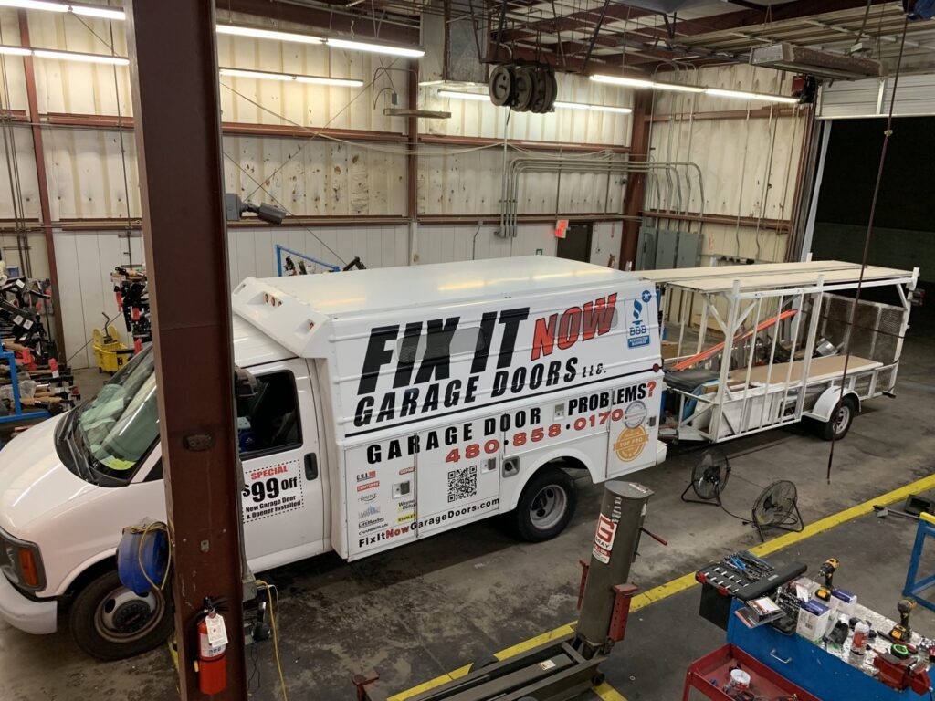The Fix It Now Garage Doors.com service truck and trailer parked inside a facility in Tempe, AZ.