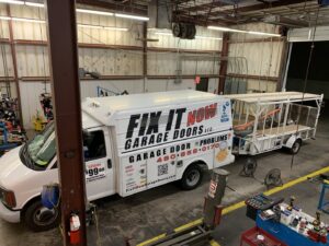 The Fix It Now Garage Doors.com service truck and trailer parked inside a facility in Tempe, AZ.