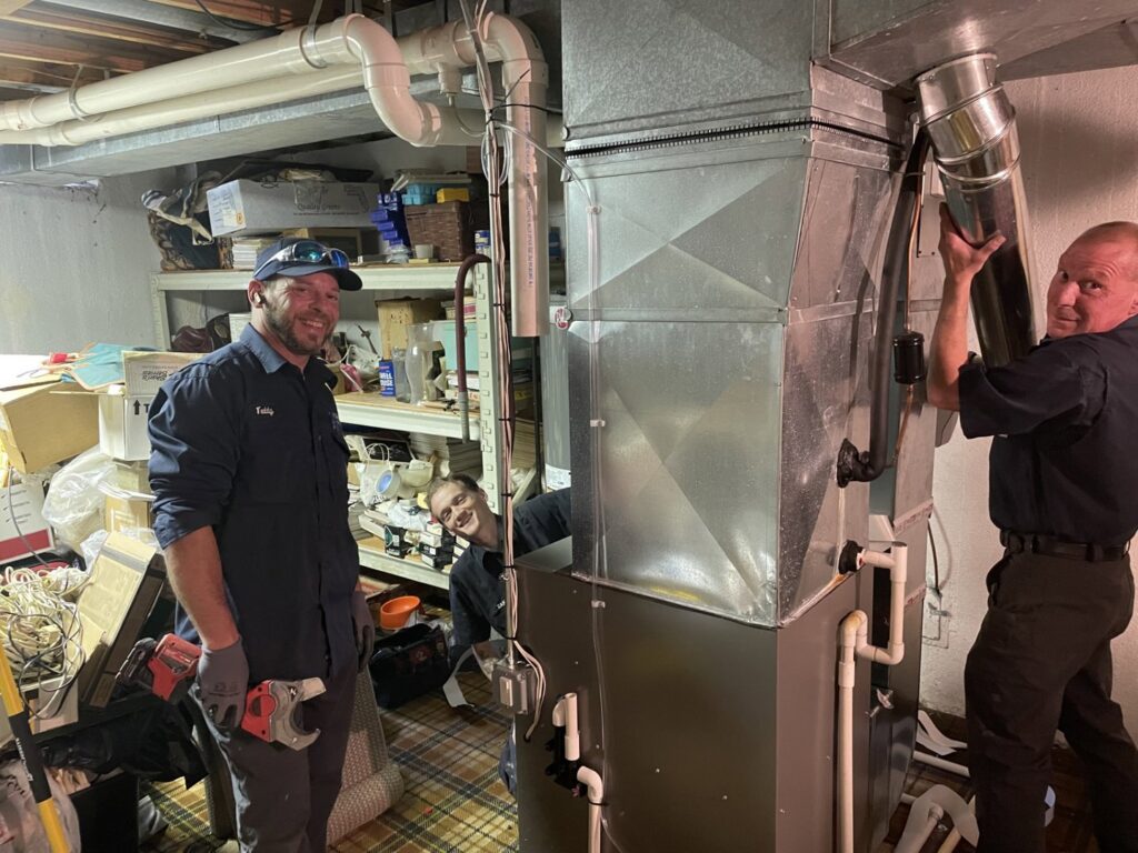 FLAME Heating, Cooling, Plumbing & Electrical technicians installing a furnace and ductwork in a basement in Warren, MI.