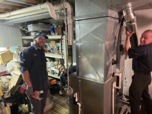 FLAME Heating, Cooling, Plumbing & Electrical technicians installing a furnace and ductwork in a basement in Warren, MI.