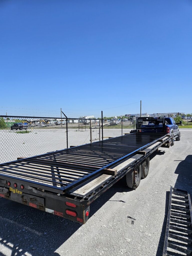 A flatbed trailer loaded with black metal fence panels, ready for installation by QD & E Fencing in Fort Worth, TX.