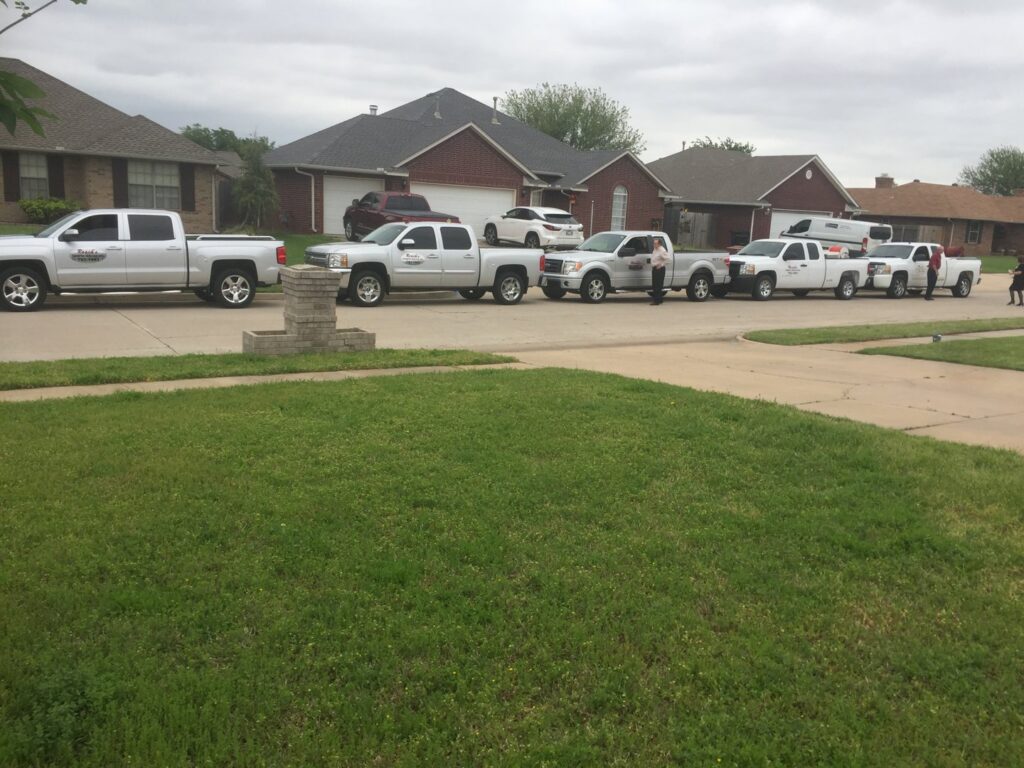 A fleet of Roach's Termite Service Inc. pest control trucks lined up on a residential street in Oklahoma City, OK