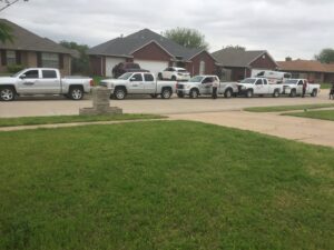 A fleet of Roach's Termite Service Inc. pest control trucks lined up on a residential street in Oklahoma City, OK