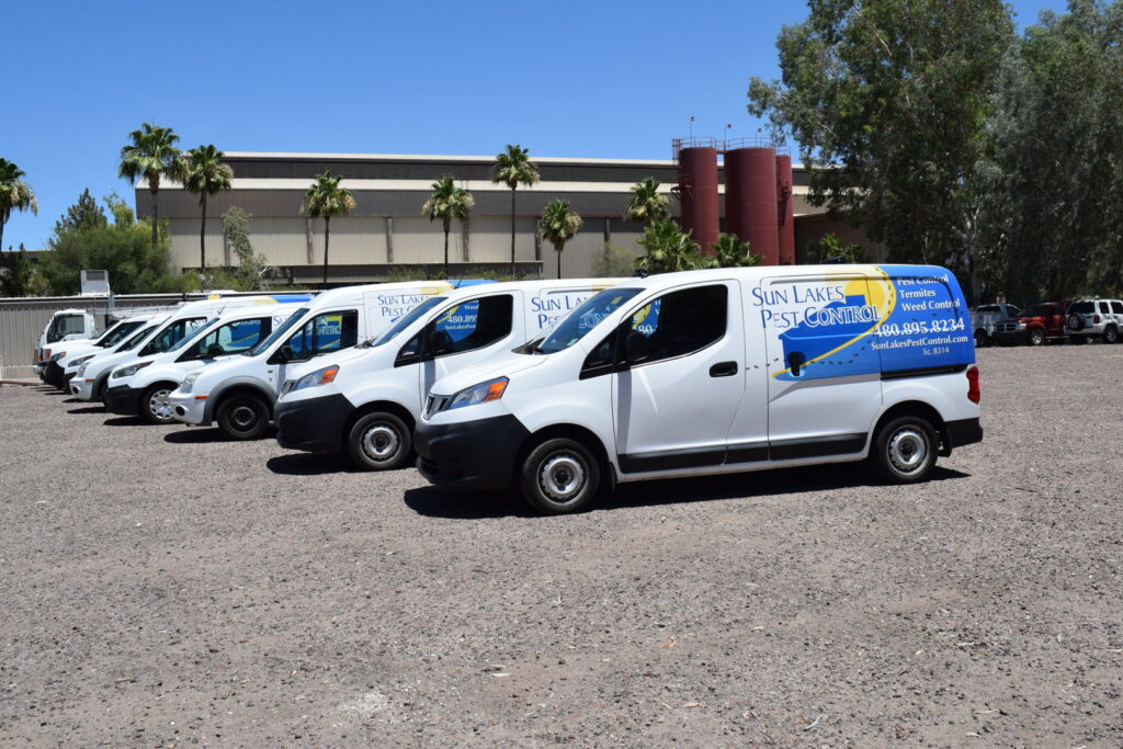 A fleet of white pest control vans and trucks parked, ready for service at Sun Lakes Pest Control in Chandler, AZ.